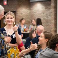 Group of people sitting and standing while talking at tables